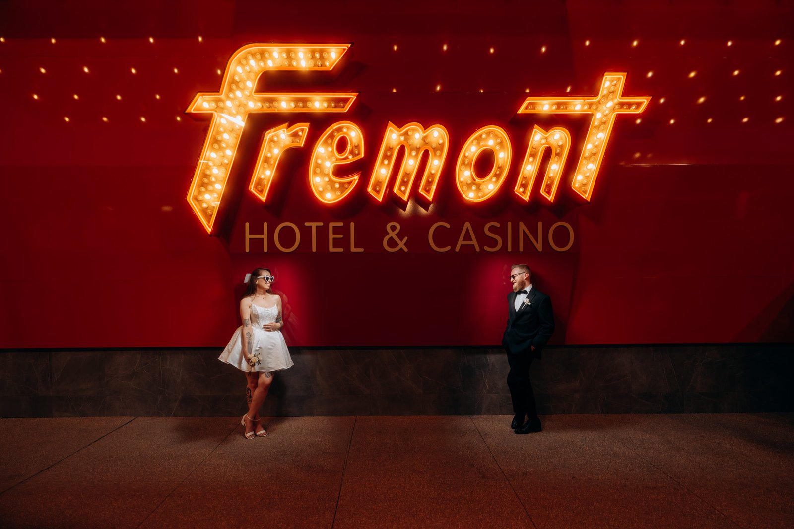 Bride and groom posing in front of the Fremont Street Experience sign during their Las Vegas elopement photoshoot.